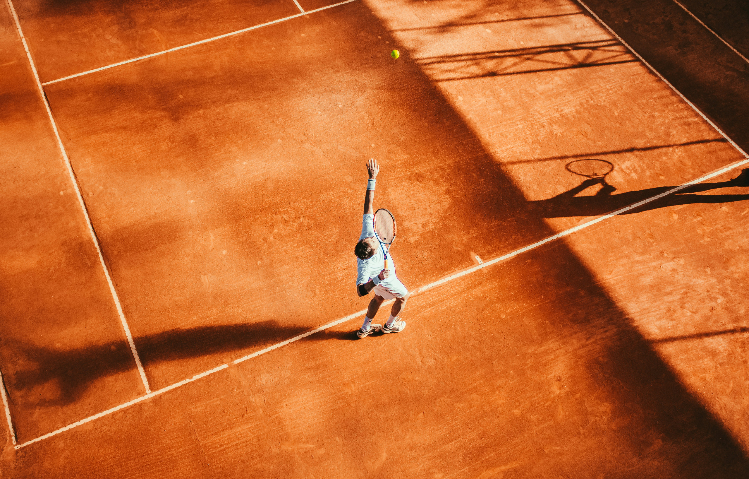 Overhead view of a tennis player serving on a clay court