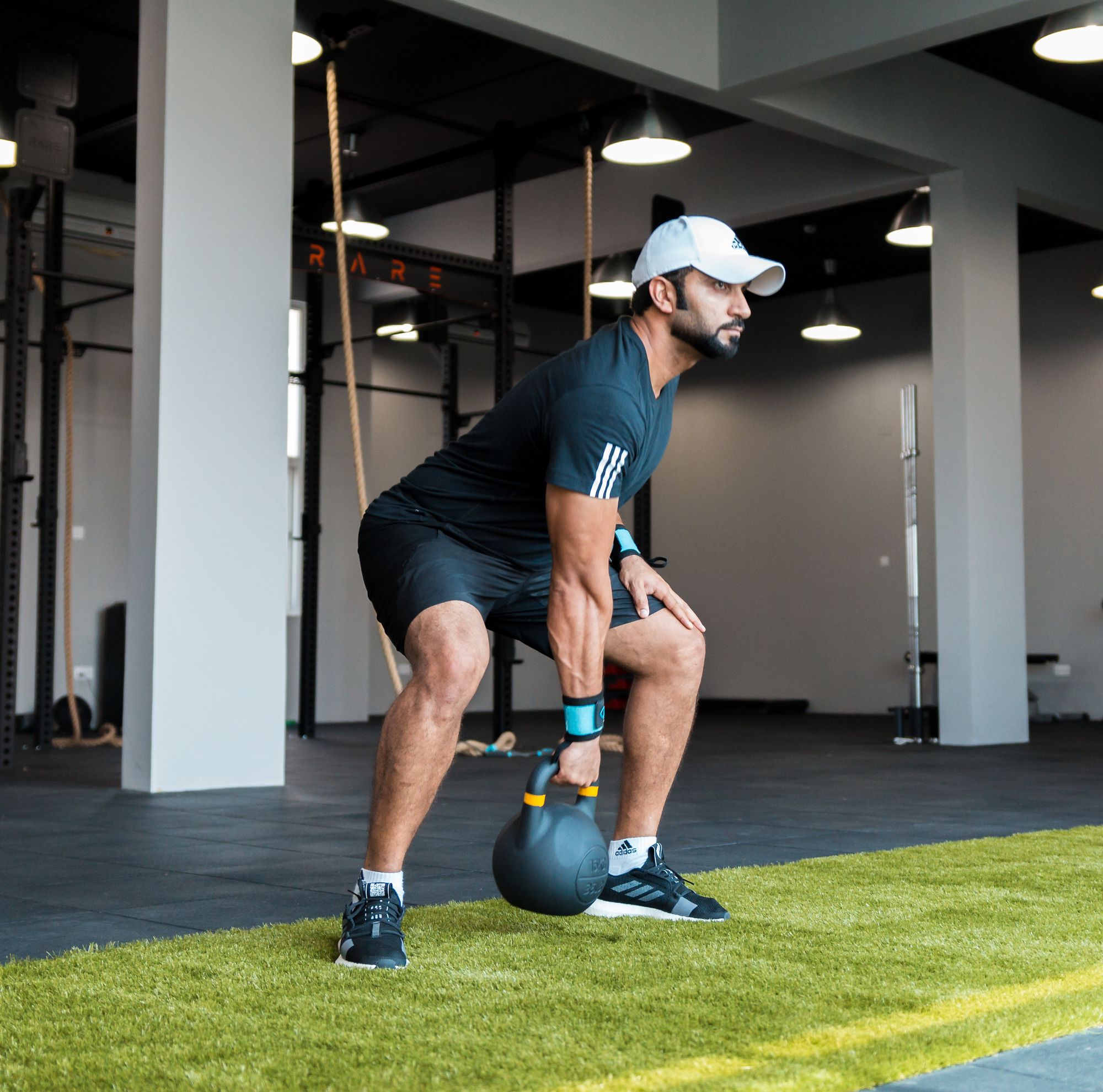An adult performing a kettlebell exercise in a functional training gym.