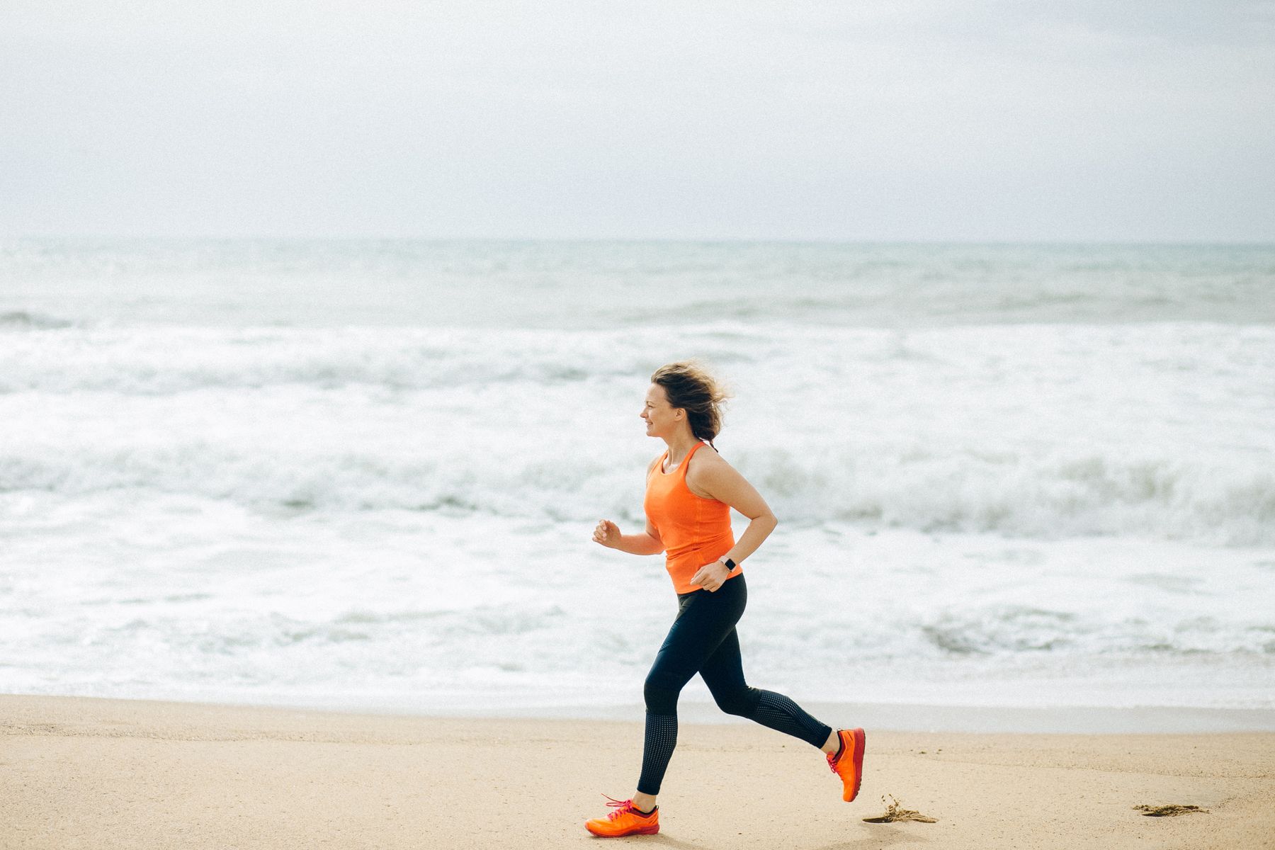 An athletic woman running beside the ocean